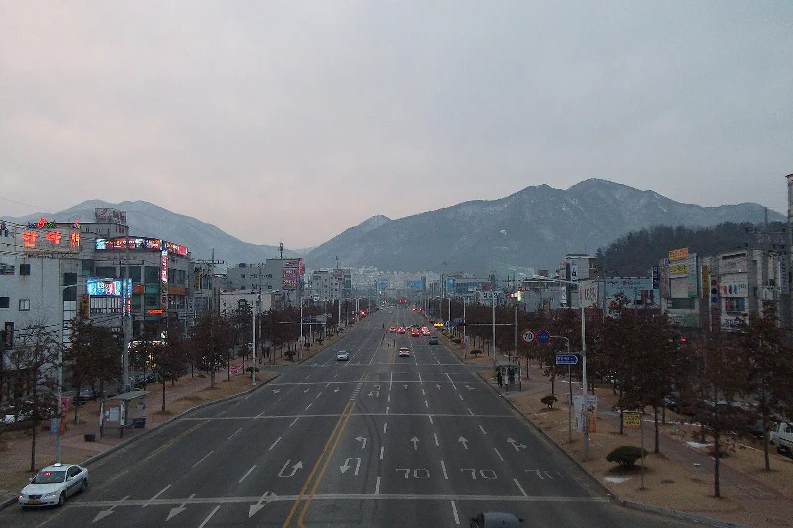 Wide main street of Gumi at dawn with mountains behind