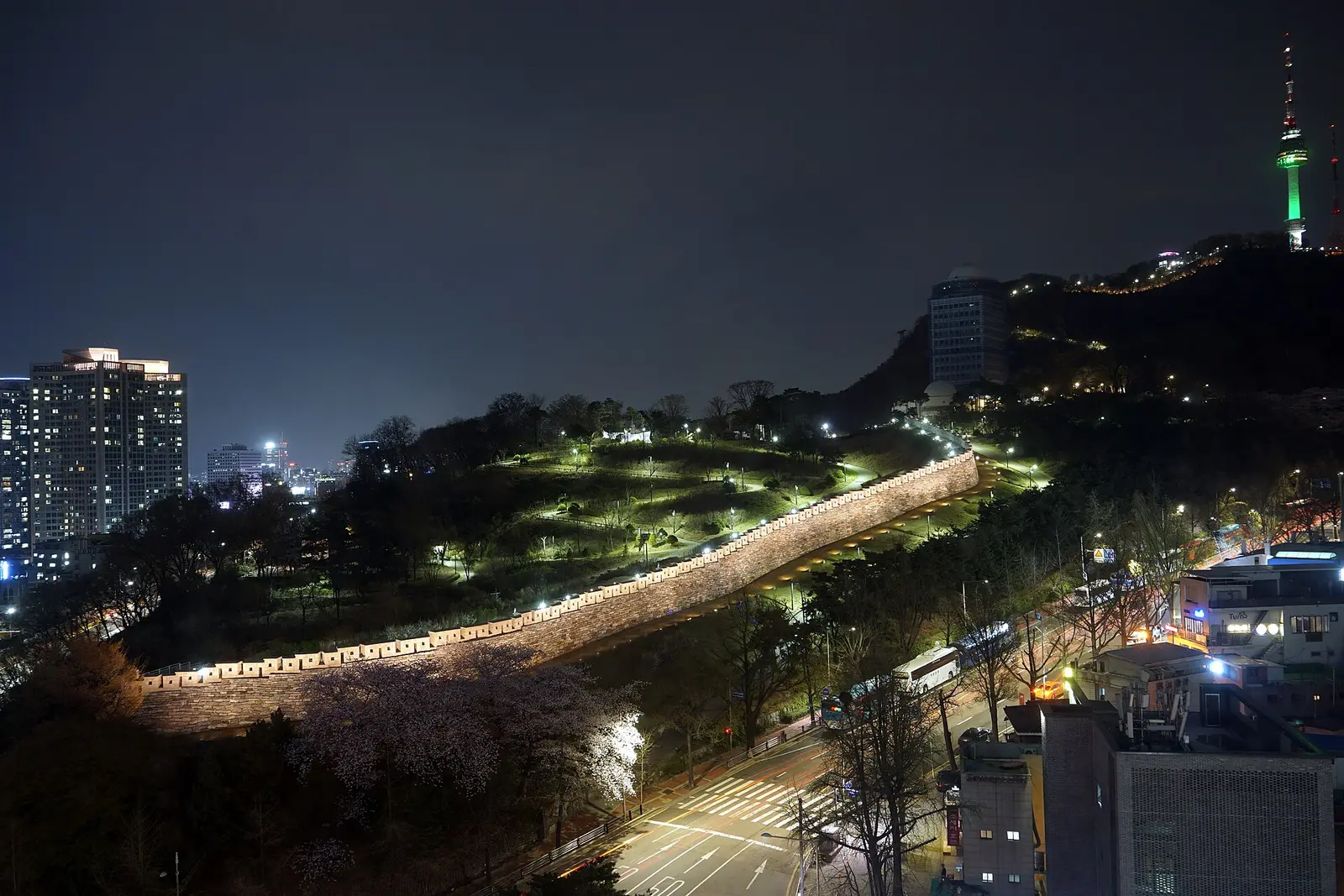 Seoul Tower on Namsan lit at night above the old city wall